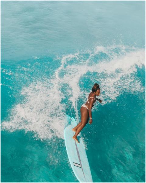 A woman surfs on a turquoise wave in Hawaii, showc