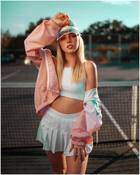 Stylish woman posing on an outdoor tennis court in