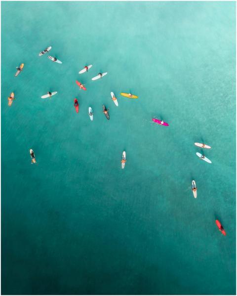 Aerial shot capturing surfers paddling in vibrant