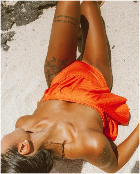 A woman in an orange swimsuit sunbathing on a sunn