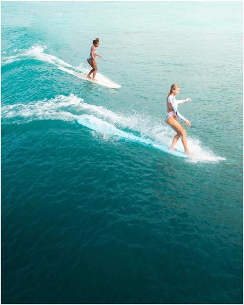 Two women surf on vibrant blue ocean waves, showca