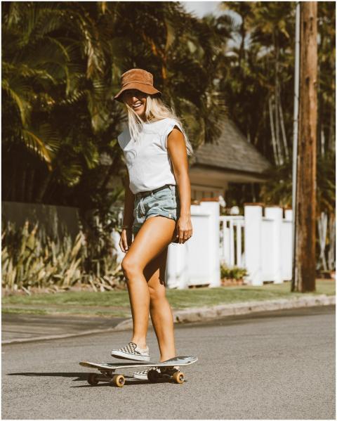 A smiling woman skateboards on a sunny residential
