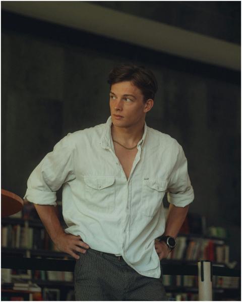 Young man in casual white shirt posing indoors wit