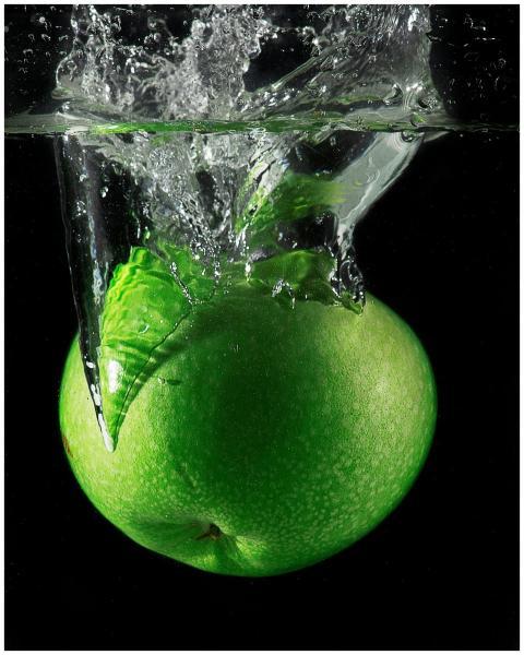 Crisp green apple diving into water with a splash
