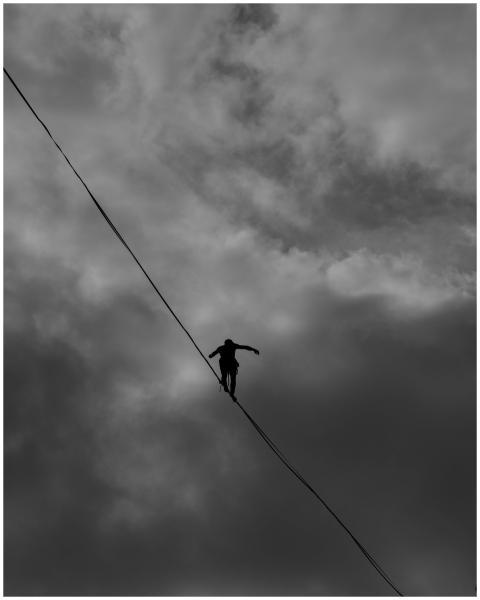 A silhouette of a person balancing on a tightrope