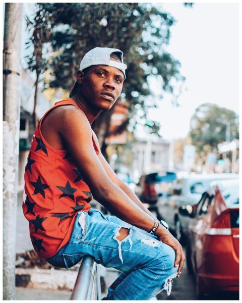 A stylish young man in a cap and tank top poses on