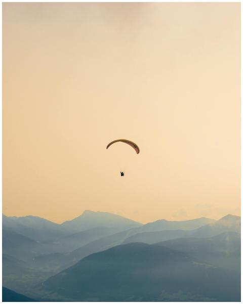 A paraglider soars gracefully over the misty, laye