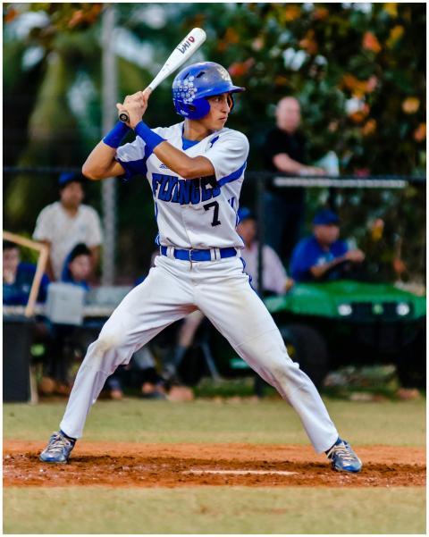 Teen baseball player in uniform ready to swing dur