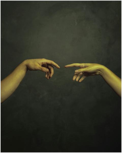 Two hands reaching towards each other against a da