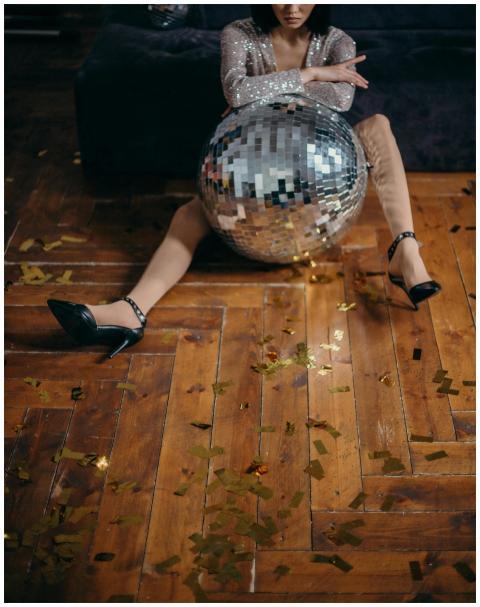 A fashionable woman sitting with a disco ball amid