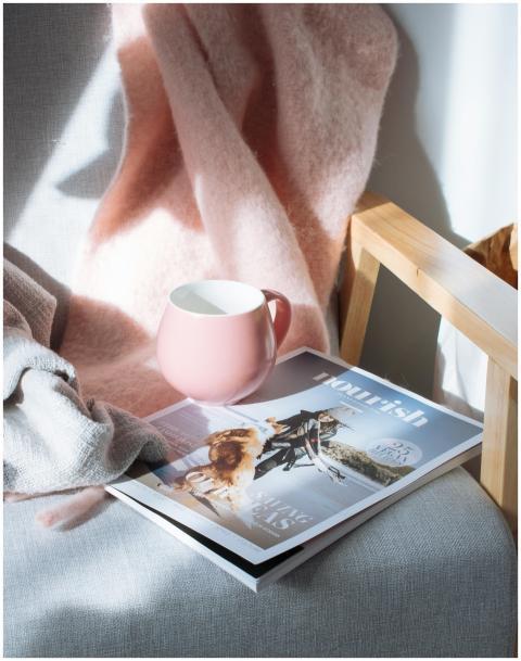 A warm scene featuring a pink mug and magazine on