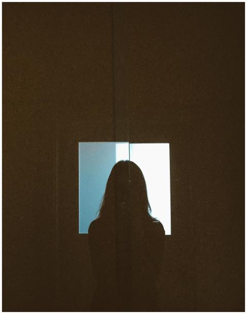 Silhouette of a woman standing before a window pro