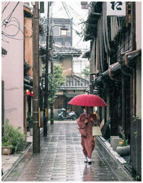 A person in a kimono walks with an umbrella in the