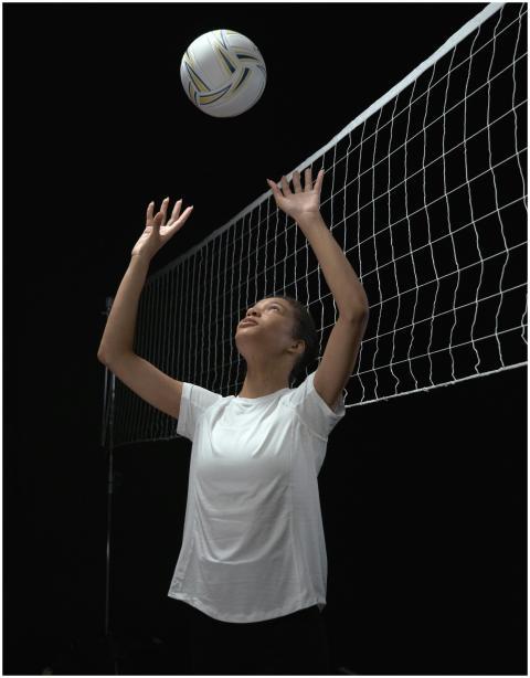 A focused female athlete playing volleyball in a s