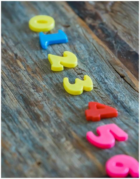 Bright plastic numbers arranged on rustic wood bac
