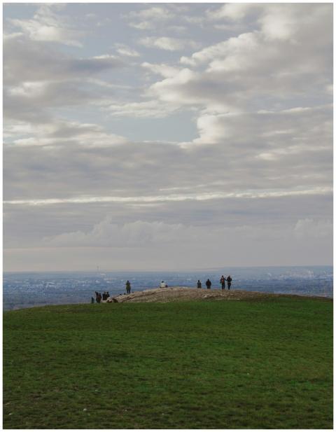 A group of people enjoying a cloudy day atop a hil