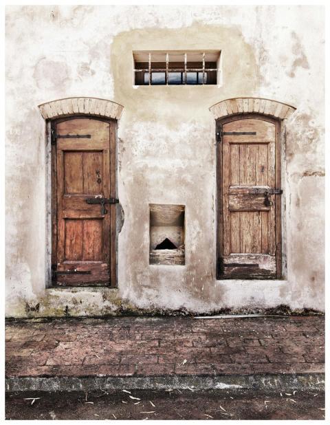 Two weathered wooden doors on an aged brick wall w