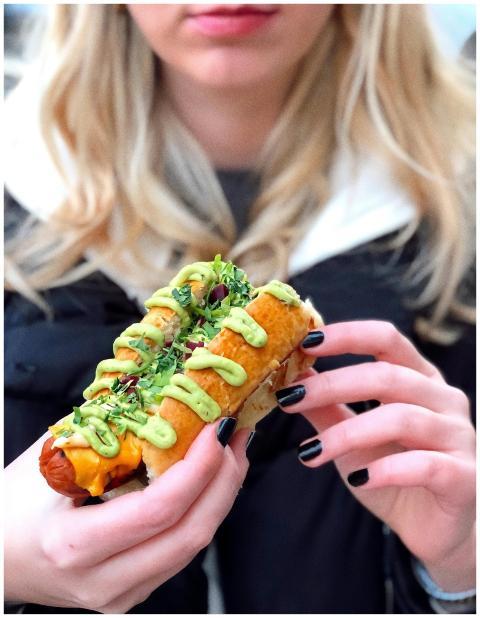 A person holding a delicious hotdog topped with av