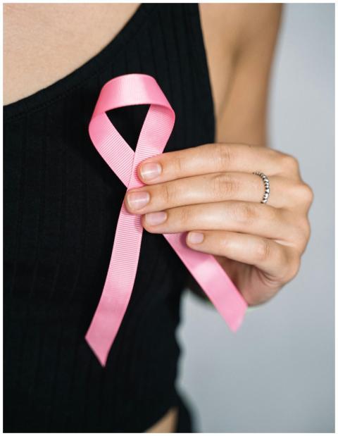 Close-up of a woman holding a pink ribbon for brea