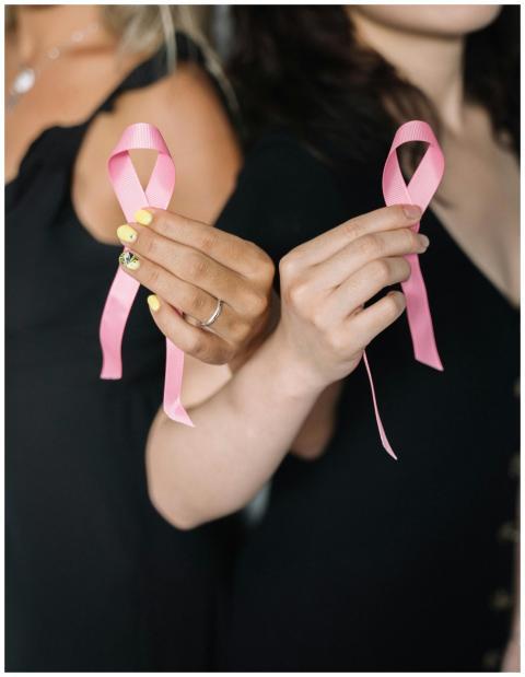 Close-up of women holding pink ribbons symbolizing