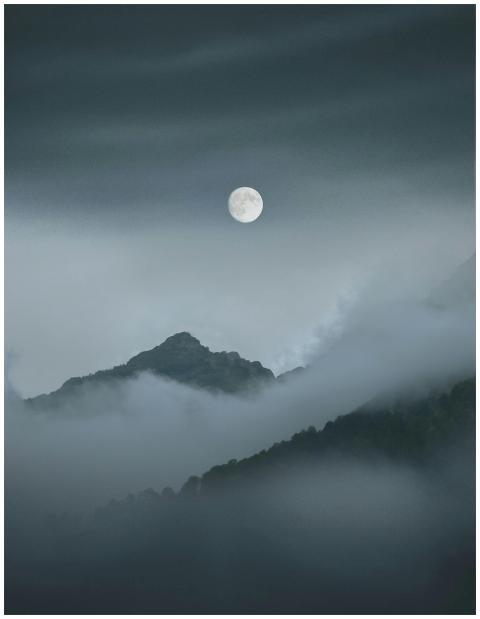 Ethereal view of a full moon over misty mountains
