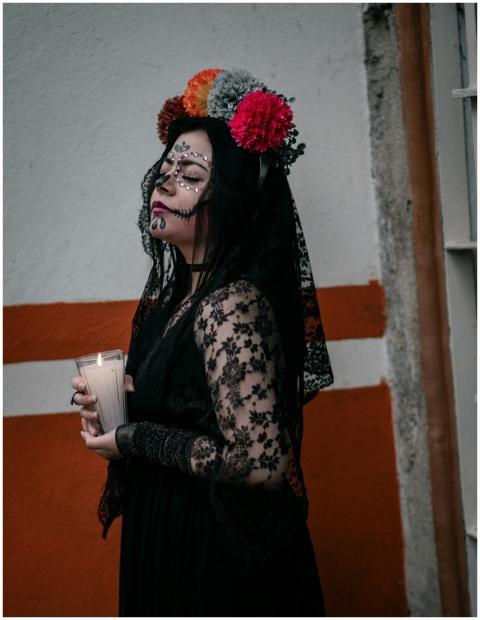 Woman dressed in Día de los Muertos attire holding