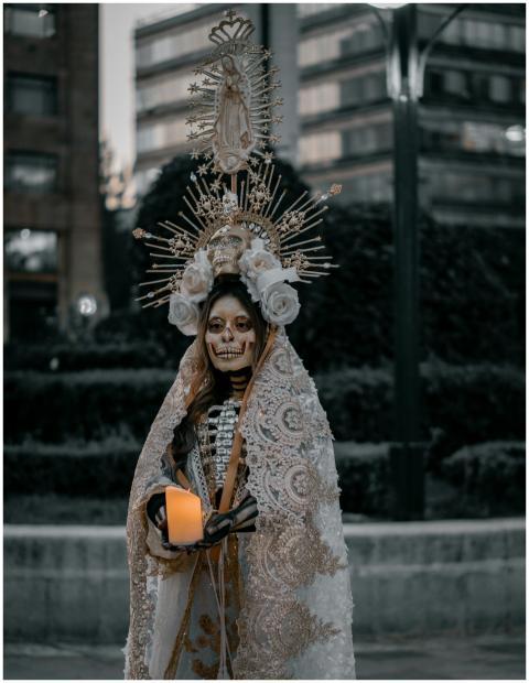 Woman in skeleton makeup and ornate costume holds