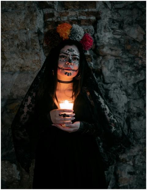 Woman with Day of the Dead makeup holding candle i