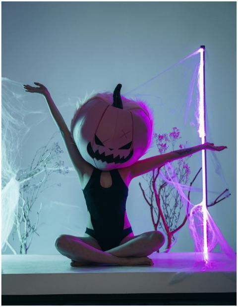 A person in a pumpkin head costume doing yoga indo