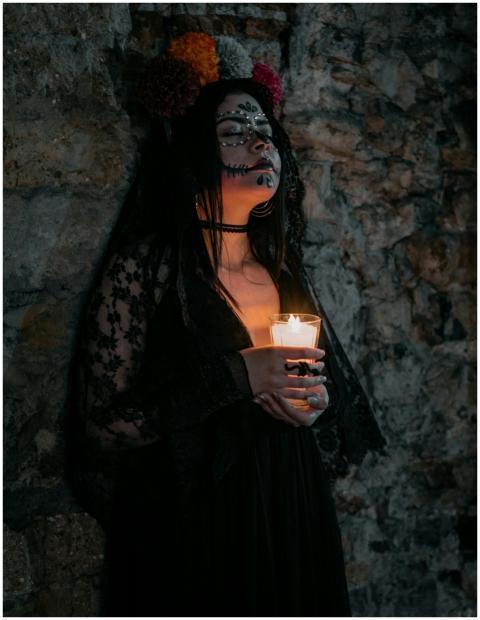 A woman in dark attire with Day of the Dead makeup
