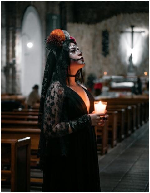Woman dressed in Day of the Dead attire holding ca