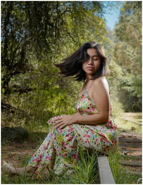 A woman sits on a railway track in a floral dress