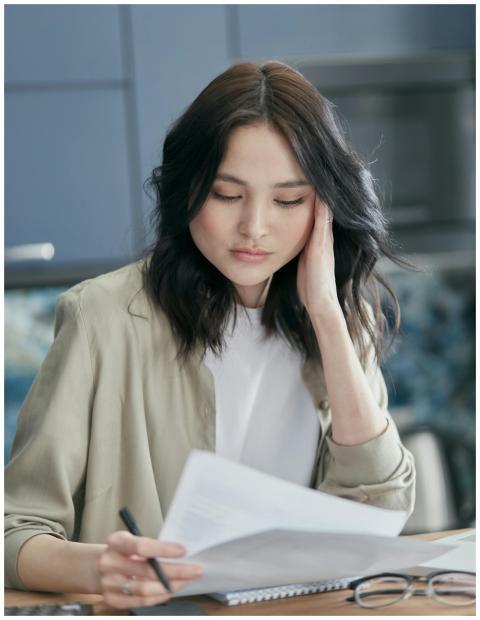 Young woman reviewing paperwork at home, focused a