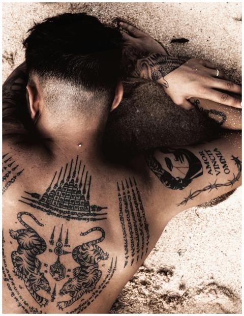 A tattooed man with intricate designs lying on a s