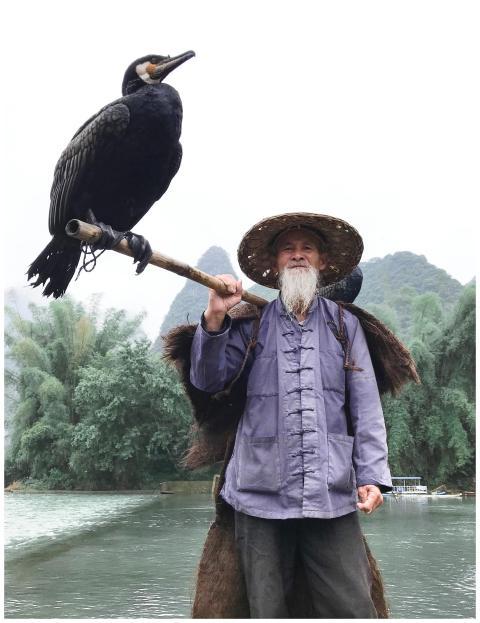 Elderly man in traditional attire with a cormorant