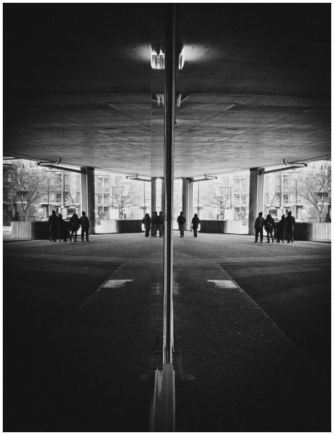 A mirrored urban scene with silhouetted people cre