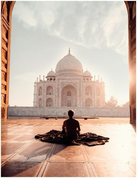 A person meditates at sunrise facing the iconic Ta