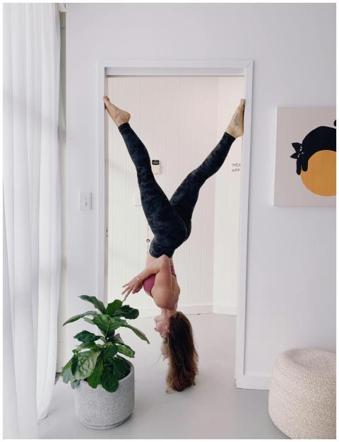 A woman balances upside down in a doorway, showcas