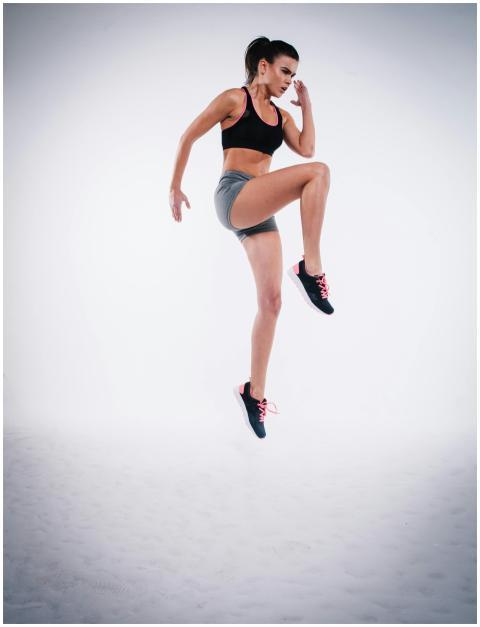 Woman in black sports bra and gray shorts performi