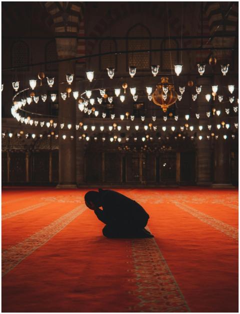 A man in silhouette kneels in prayer inside a beau