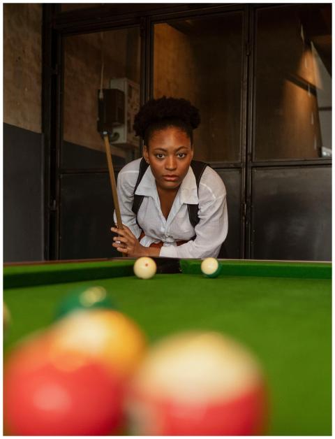 A woman concentrating on a pool game in a stylish