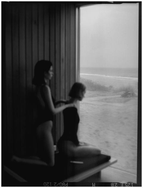 Silhouetted women in swimsuits gazing out at a tra