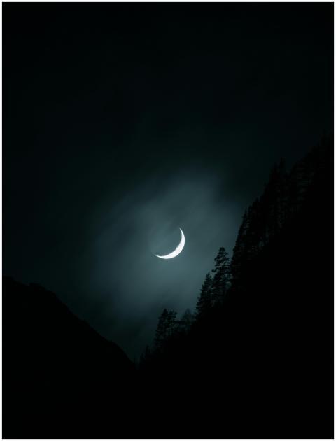 Crescent moon glowing in a mysterious night sky ov