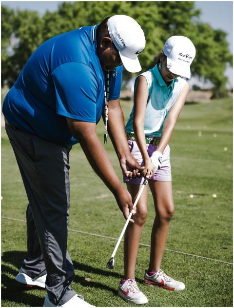 Instructor teaching a young girl golf with guidanc