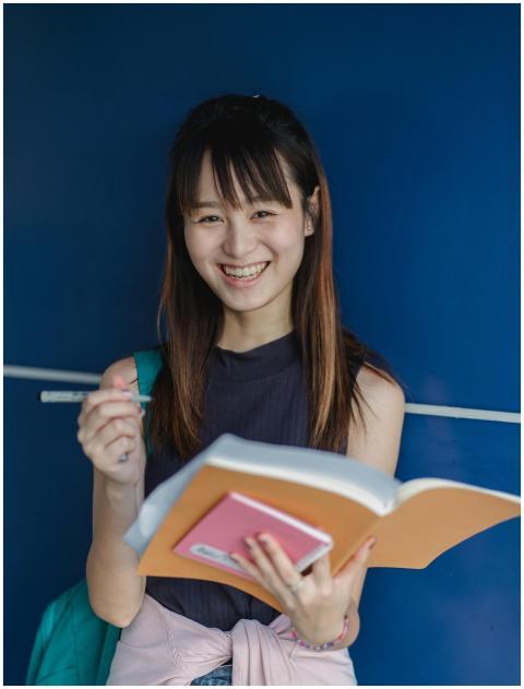 Young Asian woman smiling while studying with book