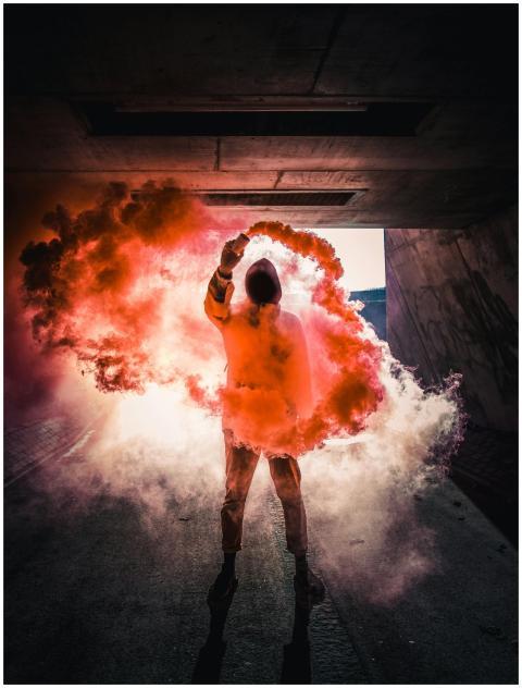 Person holding vibrant colored smoke in a dramatic