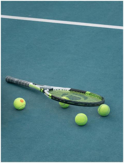 Tennis racket and balls on a blue court surface un