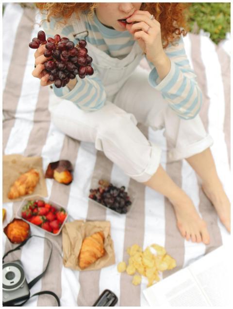 Young woman enjoying a picnic with fresh grapes an