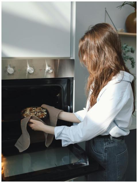Woman placing a freshly baked pie into the oven in