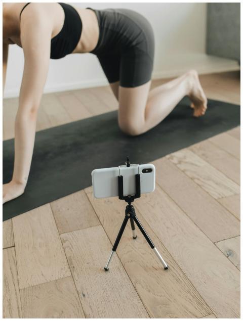 Woman practicing yoga indoors while recording with